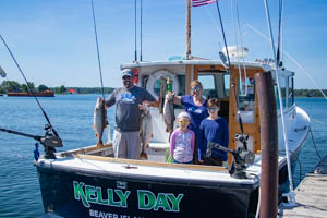 Family holding the catch of the day on the back of the Kelly Day boat